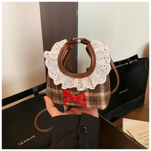 Detail of a brown plaid mini bag with white lace trim and a red sequin bow