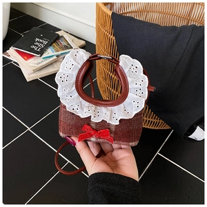 Detailed view of red plaid pet bib with white lace trim and bright red ribbon bow