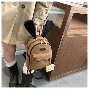 Detail of leopard print kids backpack with 3D bunny ears and plush bear charm