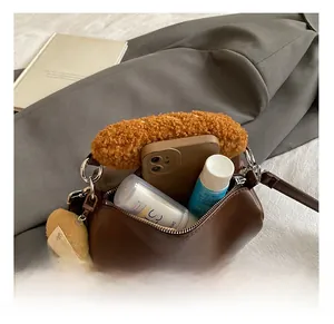 Detail of cylindrical brown leather bag interior and fuzzy caramel plush handle