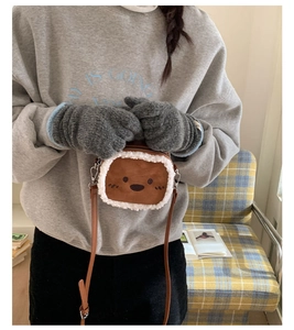 Detail view of brown plush bear crossbody bag with soft white faux fur trim and embroidery