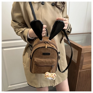 Detail of a brown matte mini backpack featuring large glossy rabbit ears and a leopard charm