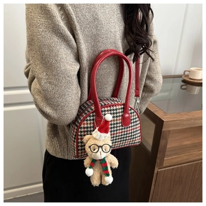 Detail of red houndstooth shell bag with cute plush bear charm on a female model