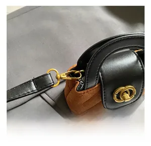 Détail macro du mini sac en daim matelassé marron avec crochet doré et cuir noir élégant