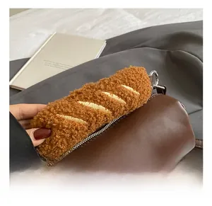Detail showing plush handle and gold embroidery on brown leather cylindrical bag