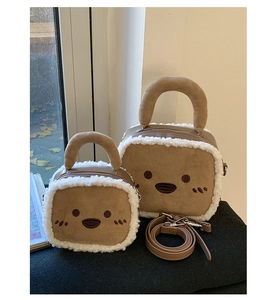 Detail view of two sizes of plush square crossbody bags with faux suede and white fur trim