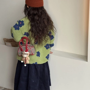 Détail d'enfant en manteau polaire vert fleuri avec sac à main pied-de-poule et ourson
