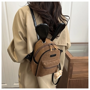 Detail of cute brown mini backpack with black rabbit ears and soft plush charm on model