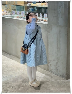Détail d'un gilet matelassé bleu clair et d'un mini sac à bandoulière bicolore pour enfant