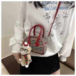 Detail of kids houndstooth handbag with red leather straps and a plush bear charm