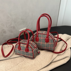 Détail de sacs à motif pied-de-poule avec anses en cuir rouge sur vêtement en laine
