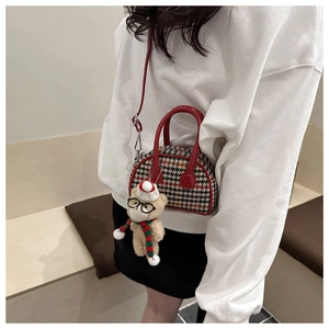 Detail of red plaid kids handbag featuring cute plush bear charm and glossy trim