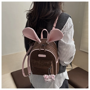 Detail of cute rabbit ear backpack with leopard print pocket and plush kitty charm