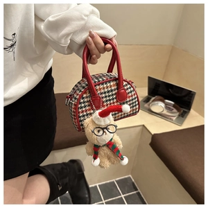 Detail of checkered mini tote bag with cute plush bear charm held by model