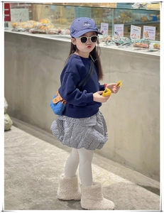 Détail d'un mini sac bandoulière matelassé bleu pour enfant avec chaîne et tenue d'automne