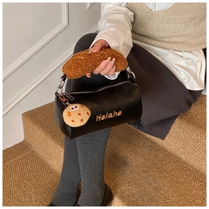 Detail of black mini cylinder bag with plush cookie charm and bread-style fuzzy handle