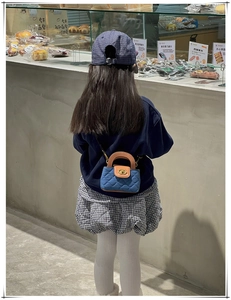 Vue détaillée du mini sac bandoulière matelassé bleu avec poignée marron et fermoir doré