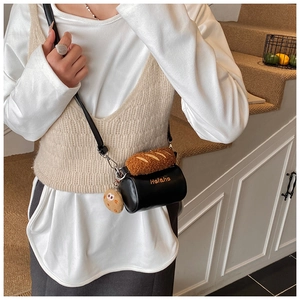 Detail of plush baguette and cookie charm on mini cylindrical faux leather bag