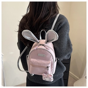 Detail of pink toddler backpack with silver rabbit ears and plush cat charm