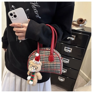 Detail of plaid shell bag for kids featuring a plush bear charm and red leather handle