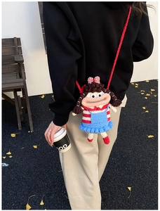 Detailed back view of a handmade crochet doll crossbody bag on a model in a scenic park