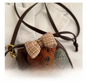 Dettaglio della borsa a tracolla per bambini con orsetto di peluche e tessuto spinato grigio