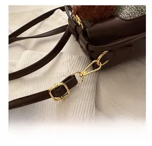 Dettaglio del gancio in metallo dorato e cinturino in pelle marrone della borsa bimbi