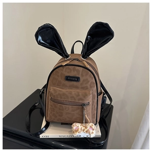 Detail of brown leopard print kids backpack with glossy black bunny ears and plush charm