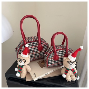 Detail of red and black houndstooth shell bags with plush bear in a cozy scene