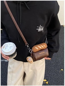 Close-up of a mini brown leather crossbody bag with fluffy baguette flap and cookie charm