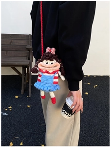 Outdoor street style shot of a handmade crochet cartoon girl doll crossbody bag for kids