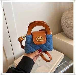 Détail du mini sac en jean matelassé avec anses en cuir marron et fermoir doré