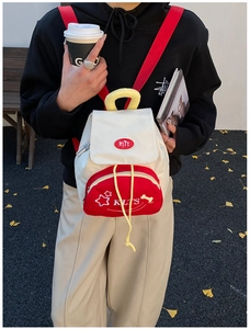 Mini star backpack for toddlers in beige and red shown in an outdoor street setting