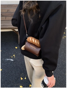 Detail shot of a mini cylinder crossbody bag with a creative plush baguette ornament