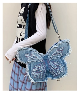 Detailed view of butterfly denim bag with frayed edges and red contrast stitching