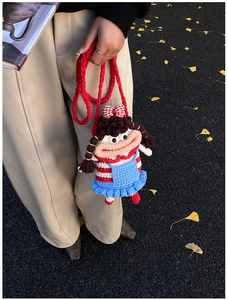 Detail of handmade crochet doll shoulder bag with big mouth and blue ruffled dress