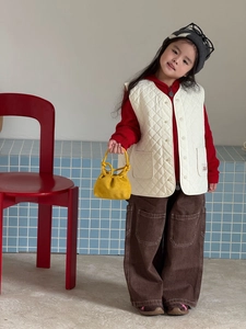 Dettaglio del gilet trapuntato crema con felpa rossa e pantaloni cargo marroni casual