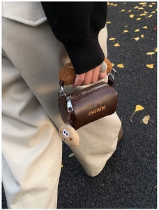 Detail of mini cylinder cookie bag with plush handle and biscuit charm on autumn street