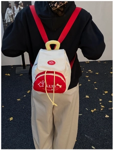 Kid back view wearing red and white star backpack with yellow straps in a park