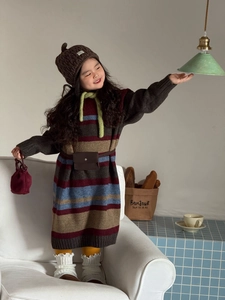 Dettaglio borsa a mano in velluto bordeaux per bambini con vestito a righe in maglia