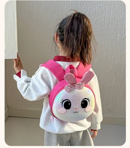 Detail of pink sequin bunny backpack with cute ears and bow on a small child's back