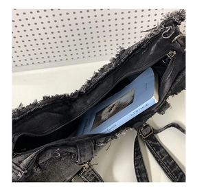 Internal view of large capacity black denim crossbody bag with raw fringe edge
