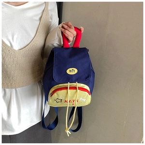 Detail of a kids' backpack with blue flap, yellow pocket, and star pattern held by a hand