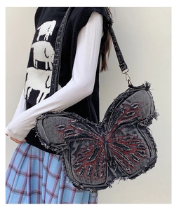 Detail of a large butterfly denim bag with red embroidery and frayed edges on a child model