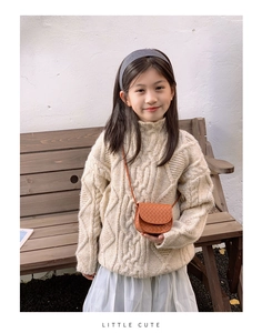 Close-up of a brown woven texture crossbody bag paired with a cream knit sweater