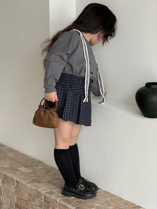 Ragazza con borsa a mano in pelle scamosciata marrone, cardigan grigio e gonna