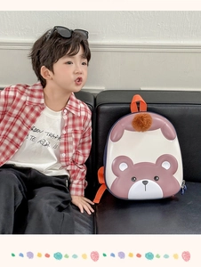Detailed close-up of a 3D bear-shaped kids backpack with orange handle and plush ball charm