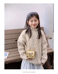 Détail macro du mini sac bandoulière doré pour enfant avec nœud en métal et chaîne