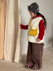 Dettaglio della borsa a tracolla gialla plissettata per bambini con un outfit alla moda