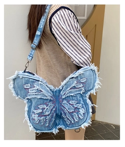Detail of blue denim butterfly cross-body bag with red embroidery and fringed edges